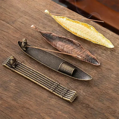 Boat shaped incense holder catching ash on a desk beside a burning stick