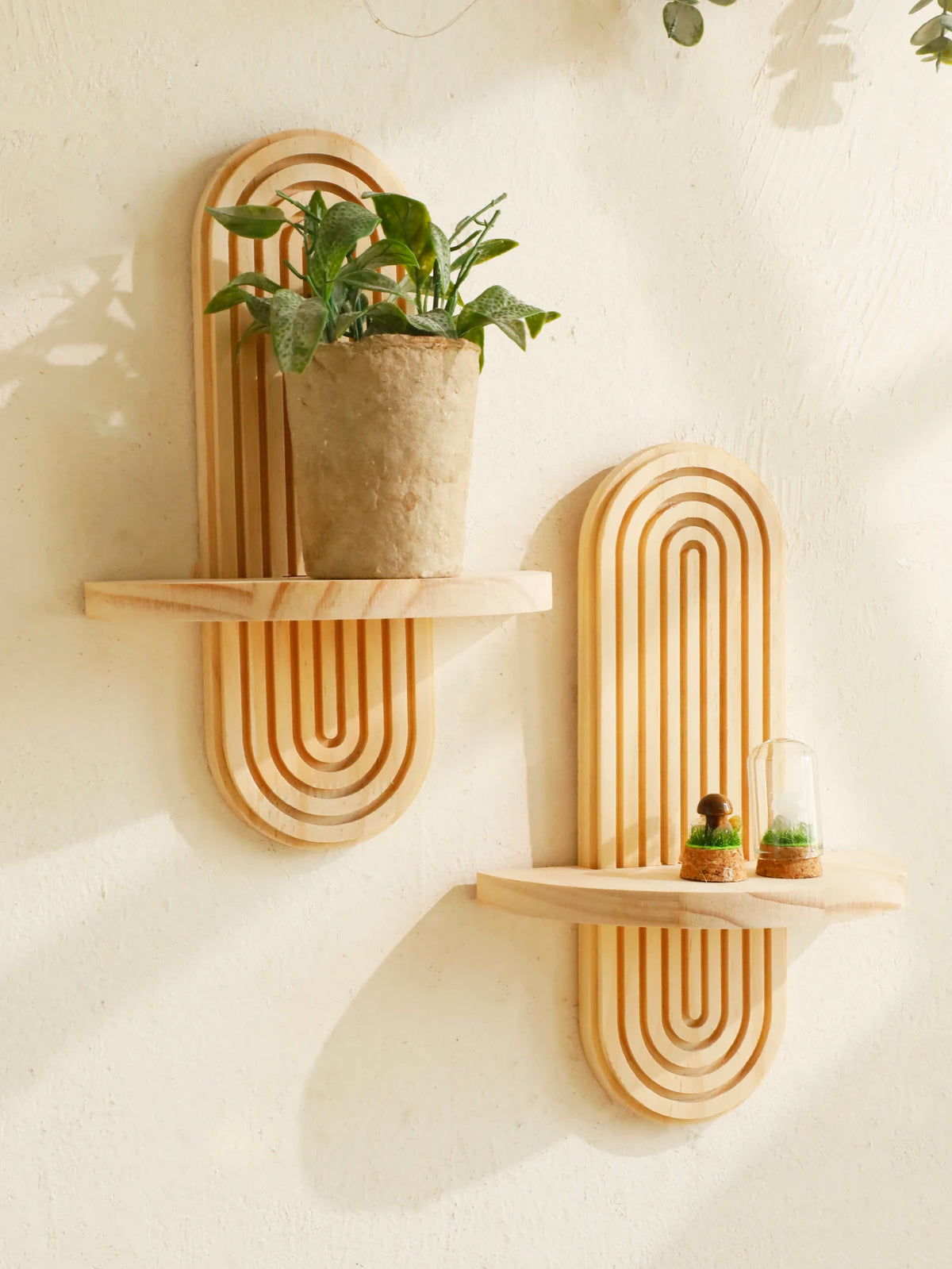 Geometric wooden wall shelf mounted on a wall holding plants and candles