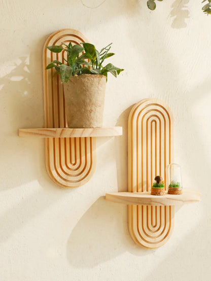 Geometric wooden wall shelf mounted on a wall holding plants and candles