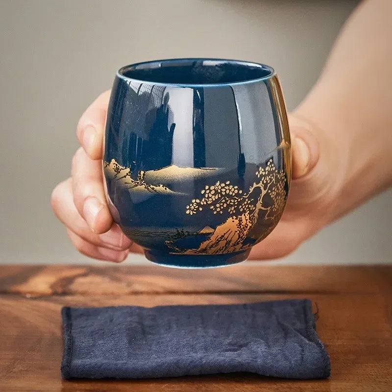Glazed Japanese master mug tea bowl held in both hands over a wooden table