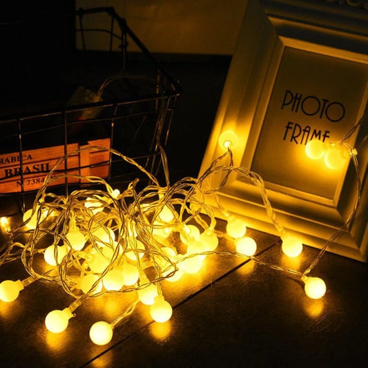 Warm LED fairy light garland draped along a bedroom mantel in the evening