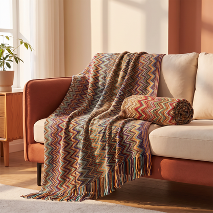 Hand knitted acrylic throw blanket with tassels draped over a sofa