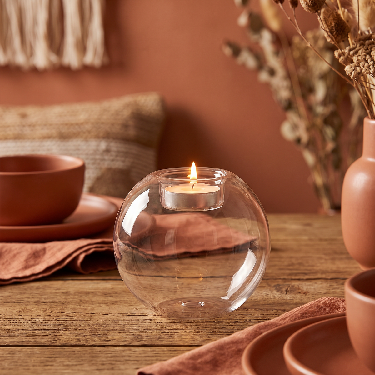 Round glass candle holder as a lit centerpiece on a dining table