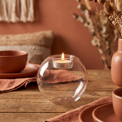 Round glass candle holder as a lit centerpiece on a dining table