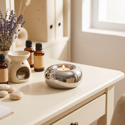 Silver electroplated circular ceramic candle holder with lit tea light on a coffee table