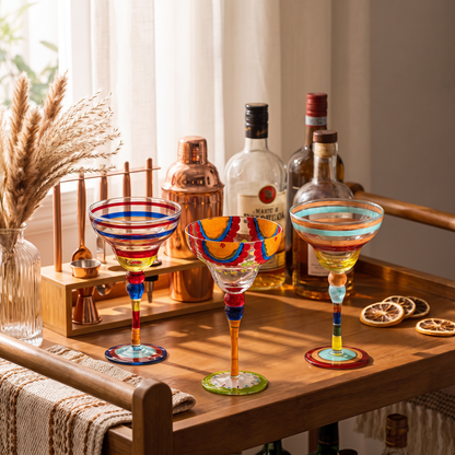 Colored coupe cocktail glasses on a bar cart, catching the light at a home gathering
